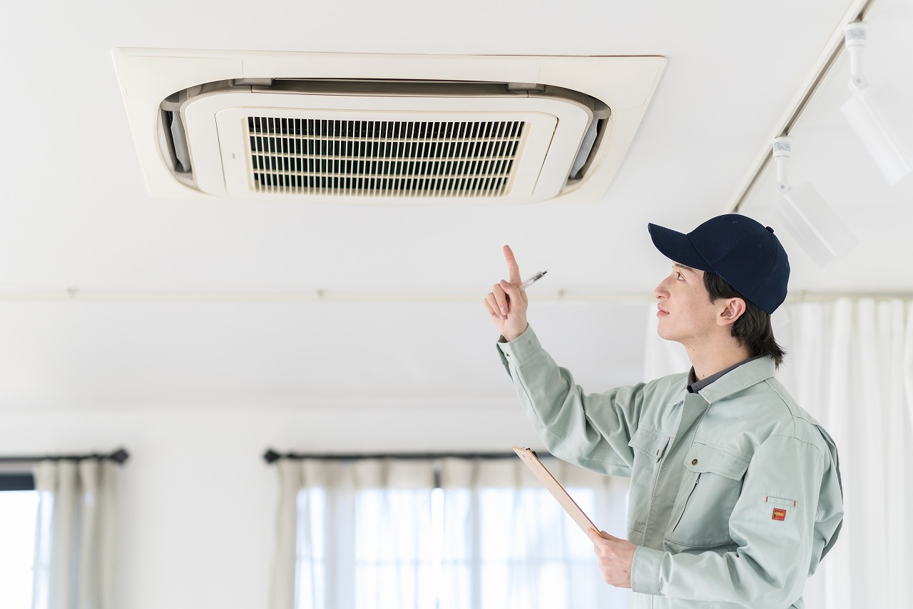 室内のエアコン設備を点検するスタッフ